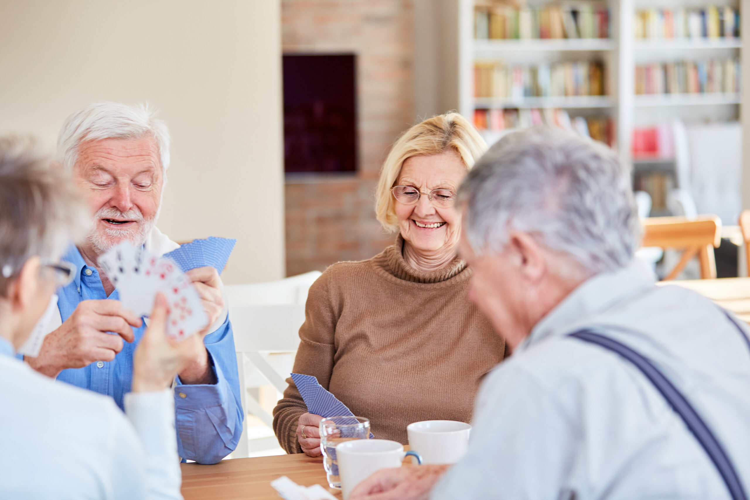 Senior retired friends play cards in their spare time or at retirement home