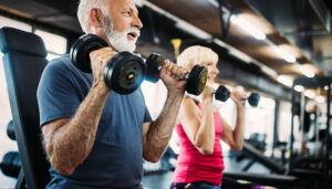 Mature fit man and woman doing exercises in gym to stay healthy
